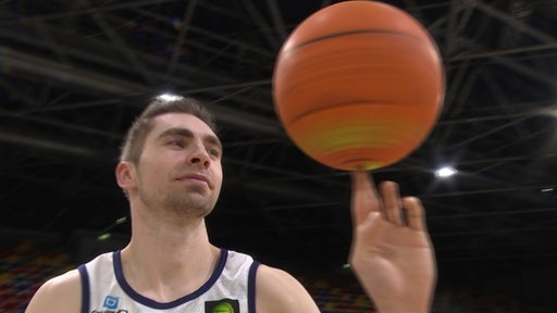 Der Basketballspieler Adrian Breitlauch balanciert einen drehenden Ball auf seinem Finger