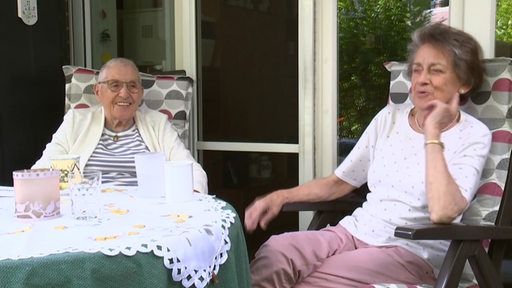 Die beiden Schwestern Felicitas Griep und Bea Spiller sitzen auf einer Terasse.