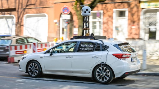 Ein Auto mit einem Stativ auf dem Dach fährt durch eine Stadt