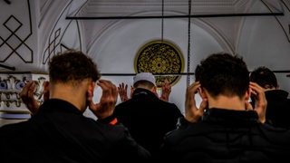 Rückenansicht junger Männer, die in einer Moschee beten