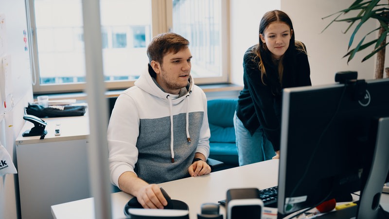 Zwei junge Menschen in einem Büro an einem Schreibtisch