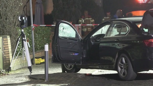 Die Fahrertür eines Autos steht offen. Im Hintergrund ist ein Absperrband und Feuerwehrmänner zu sehen.