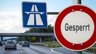 Befahrene Autobahn von Autos mit Schild mit "Sperrung"