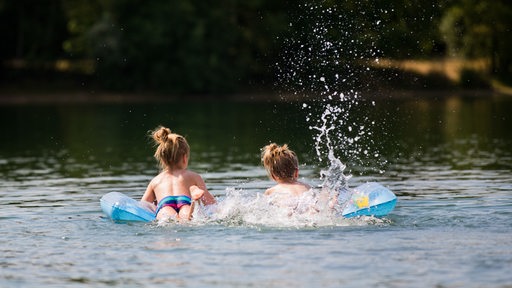 Kinder baden mit Luftmatratze in einem See.