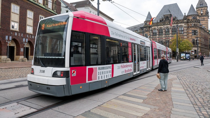 Eine Frau steht vor einer Straßenbahn in Bremen. 