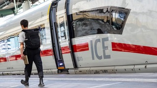 Ein Mann läuft auf dem Bahnsteig neben einem ICE.
