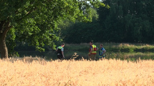 Einsatzkräfte der Polizei und Feuerwehr stehen am Baggersee in Bakum