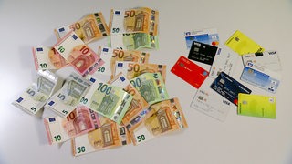 Bargeld und EC karten liegen nebeneinander auf einem Tisch.