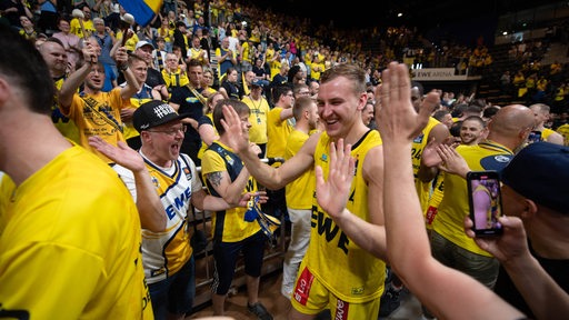 Basketball-Profi Artur Konontsuk klatscht strahlend nach dem Sieg bei den Fans der Baskets Oldenburg ab.