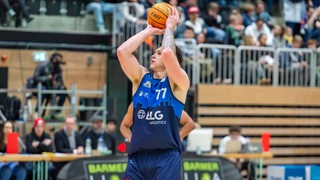 Der Basketball-Profi Anzac Risetto von den Eisbären Bremerhaven hält den Ball über seinem Kopf, bevor er wirft.