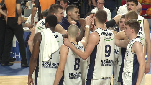 Die Basketballmannschaft der Eisbären Bremerhaven stehen nach einem Spiel alle gemeinsam im Kreis.