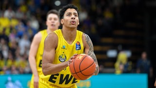 Basketballer Eli Brooks hält den Ball in beiden Händen und setzt an zum Wurf.