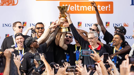 Die Basketball-Nationalspieler jubeln und recken den WM-Pokal in die Höhe.