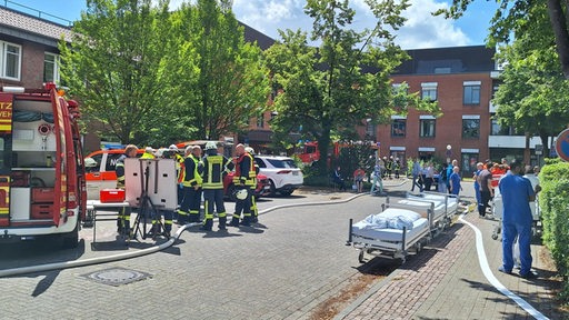 Vor dem Bassumer Krankenhaus stehen mehrere Feuerwehrmänner und Krankenhausmitarbeiter.