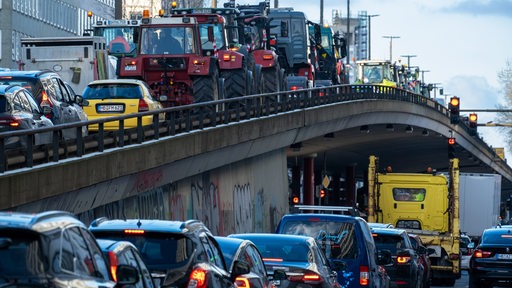 Traktoren stehen auf der Hochstraße in Bremen. Auf der Straße darunter stehen Autos im Stau.