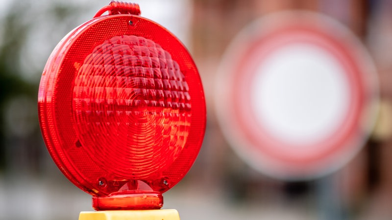 Eine rote Warnleuchte hängt an einer Baustelle vor einem Verkehrsschild