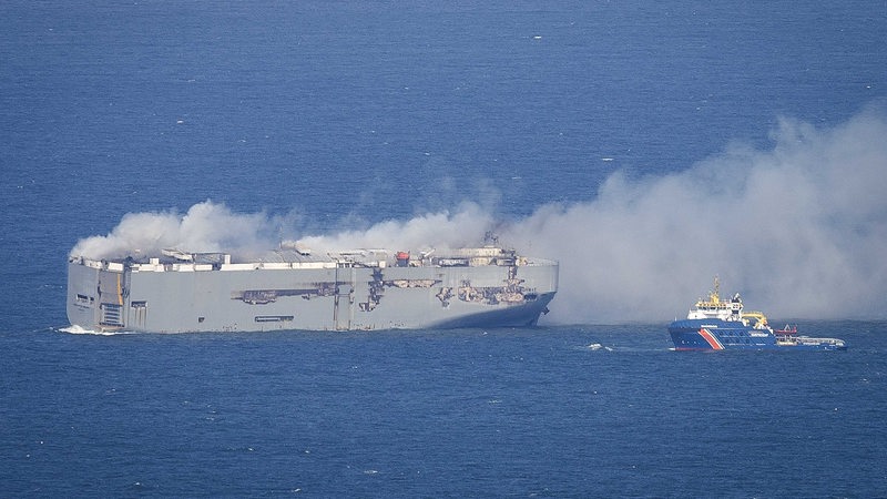 Der Autofrachter "Freemantle Highway" brennt in der Nordsee. Ein kleines blaues Schiff liegt vor ihm.