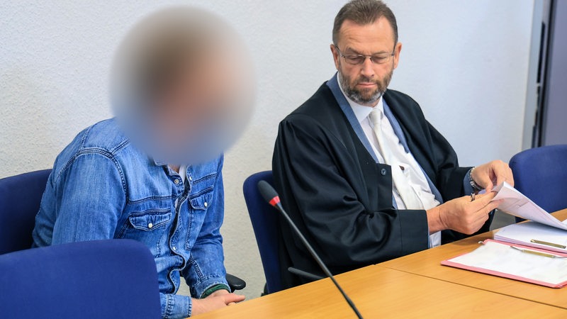 Ein Bestatter (l) sitzt neben seinem Verteidiger Bernd Leonhard zum Auftakt seines Berufungsverfahrens in einem Saal des Landgerichts Oldenburg. Der Angeklagte soll zwischen 2016 und 2019 mehrere Urnen bewusst mit anderer Asche, Staub oder Dreck befüllt und beigesetzt haben. 