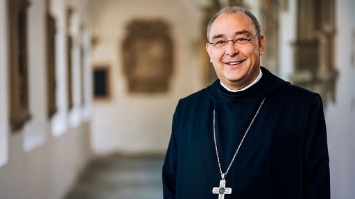 Weihbischof Dr. Dominicus Meier steht in einem sakralen Gebäude und schaut freundlich in die Kamera.