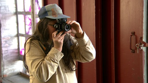 Eine Frau der Bremer Blaumeier Gruppe im Shooting am Fotografieren. 