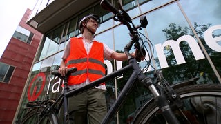 Buten un binnen Reporter Johann Weckenbrock steht mit Helm und Warnweste neben seinem Fahrrad.