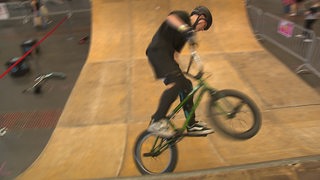 Ein Junge fährt mit einem BMX-Rad durch eine Halfpipe.