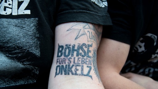 Ein Fan der Band Böhse Onkelz im Publikum zeigt auf dem Konzert sein Tattoo mit dem Schriftzug "Böhse Onkelz - Für's Leben"