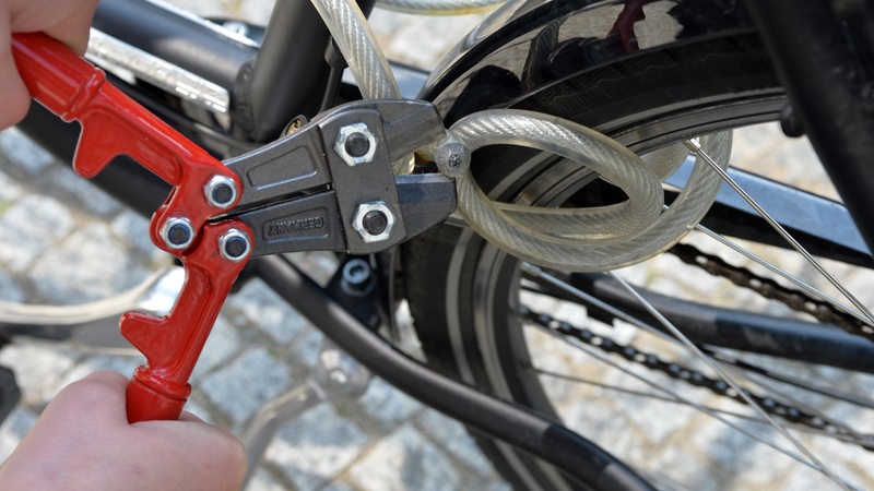 Ein Bolzenschneider durchtrennt ein Fahrradschloss.