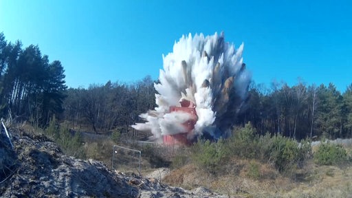 Die Sprengung einer Bombe, auf der rote Container zur Sicherung stehen.