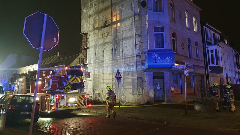 Ein Gebäude in einer Straße, davor ein Feuerwehrwagen.