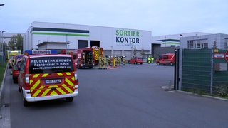 Einsatzkräfte der Feuerwehr stehen vor einer Sortieranlage