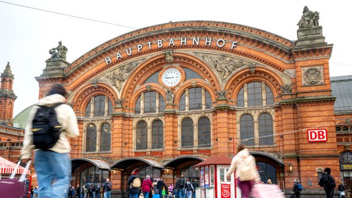 Reisende mit Koffern laufen zum Bremer Hauptbahnhof. 