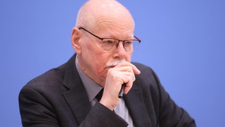 Ulrich Mäurer sitzt auf dem Podium und schaut konzentriert.