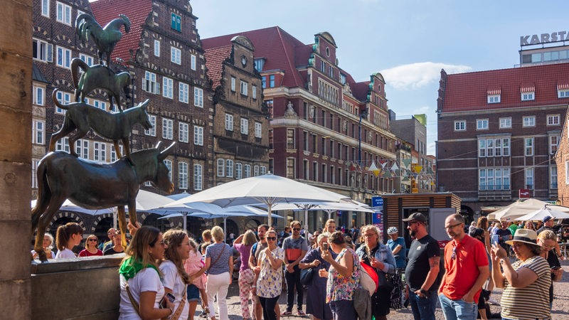 Touristen stehen vor der Statue der Stadtmusikanten und machen Fotos.