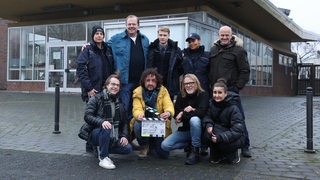 Acht Personen stehen für ein Gruppenbild zusammen.