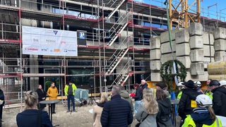 Mehrere Menschen stehen beim Richtfest um den Neubau einer Grundschule in Bremerhavne.