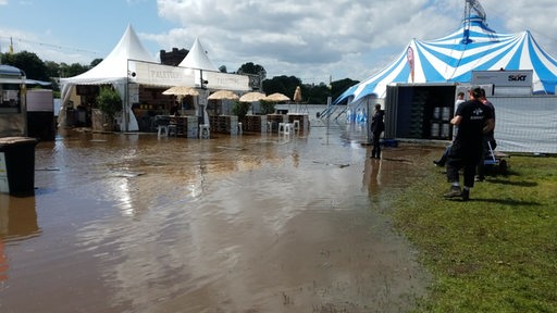 Buden und Zelte der Breminale 2024 spiegeln sich im Hochwasser.