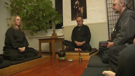 Mehrere Buddhisten Meditierenin und sitzen in einem Kreis.