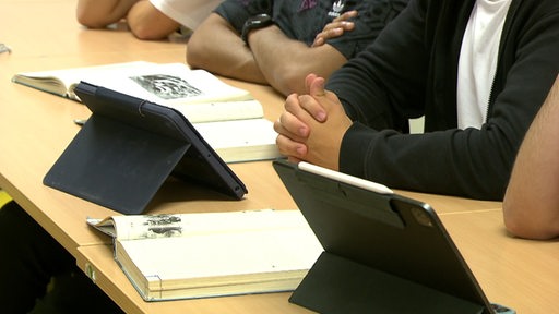 Es liegen mehrere Bücher und Tabletts auf den Tischen in einer Schule.