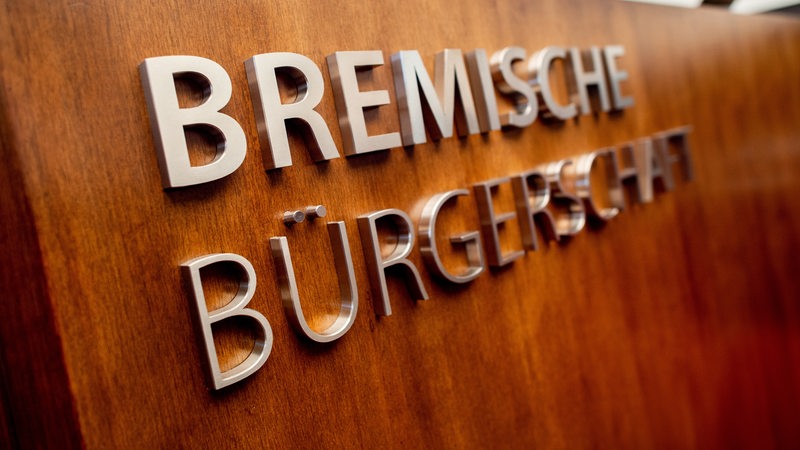 Ein Schriftzug hängt an einem Rednerpult im Plenarsaal der Bremischen Bürgerschaft. 