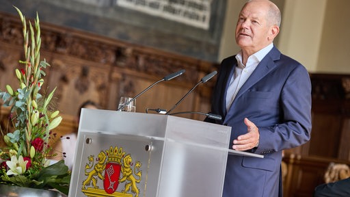 Ein Mann, Bundeskanzler Olaf Scholz, steht an einem Rednerpult.