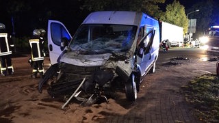 Ein bei einem Unfall demolierter Kleintransporters steht auf einem abgesperrten Bürgersteig.