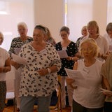 Eine Gruppe älterer Menschen hält Zettel in der Hand und singt gemeinsam.