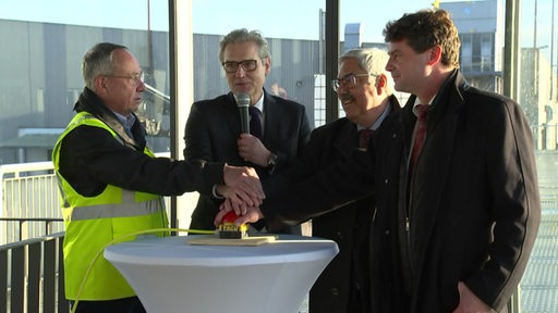 Vier Männer drücken auf einen Startknopf in Bremerhaven. 