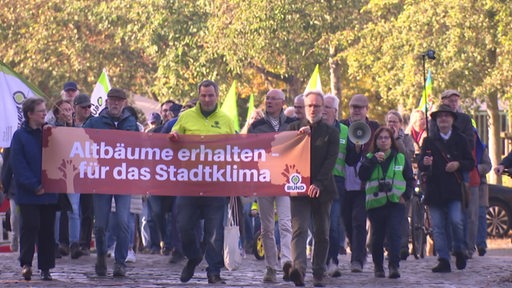 Eine Gruppe von Personen steht während einer Demonstration hinter einem Banner.