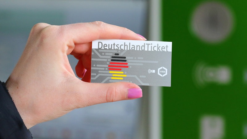 Eine Hand hält ein Deutschlandticket.