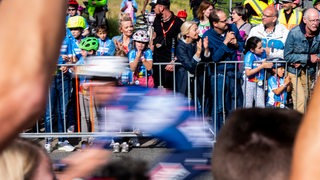 Zuschauer bei der Deutschland Tour in Bremen am Streckenrand hinter einer Absperrung.