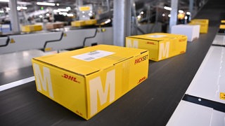 DHL-Pakete liegen auf einem Band