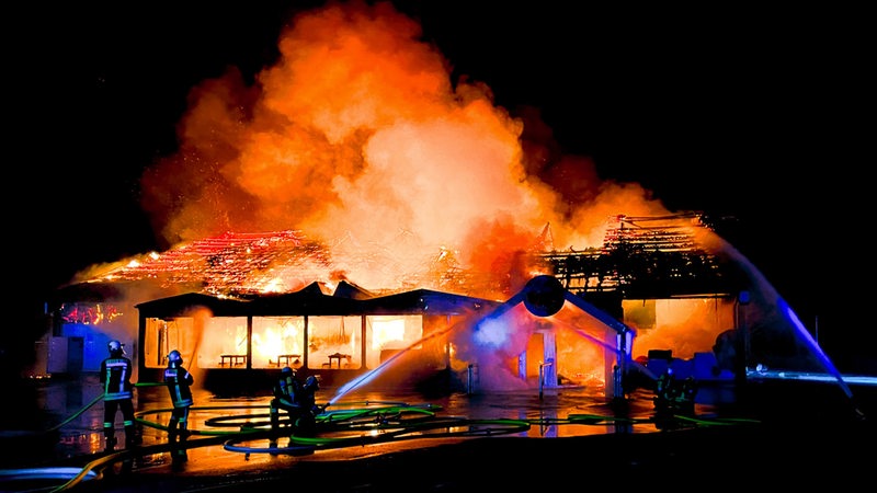 Einsatzkräfte der Feuerwehr löschen eine brennende Disco.