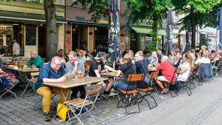 Menschen sitzen in der Außengastronomie im Bremer Ostertorviertl.